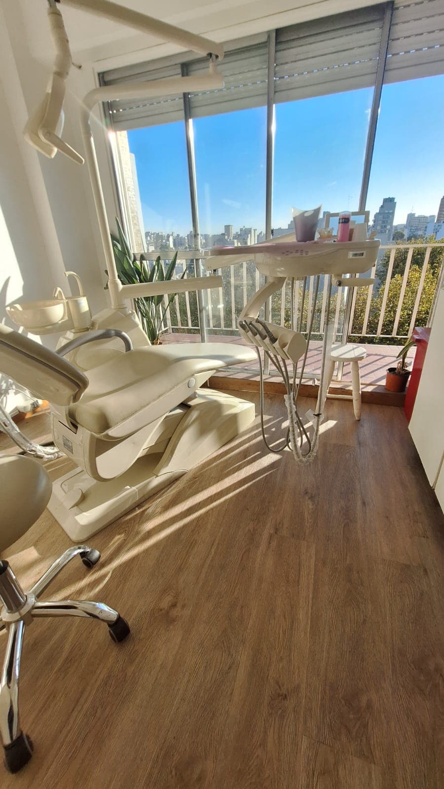 Perspectiva del sillón dental y unidad frente a la vista urbana y el cielo despejado.